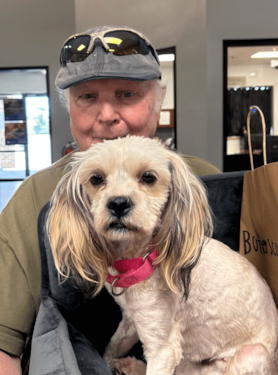 a man adopting a small white dog