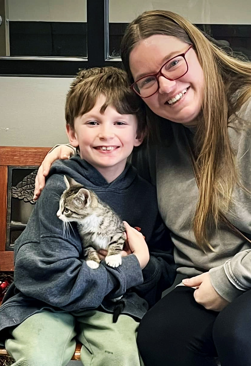 a cat getting adopted by a mother and son